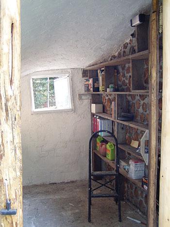 The interior of the shed has been plastered with gypsum, whitewashed, and outfitted with shelves.