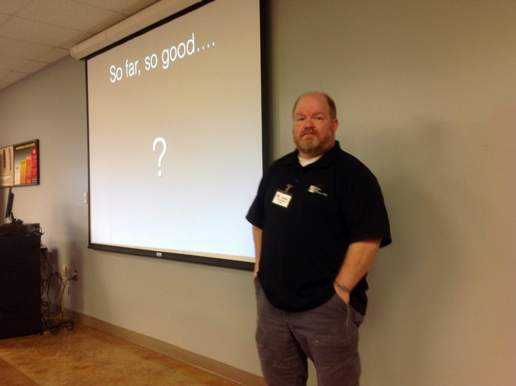 William Aprill standing in front of a screen