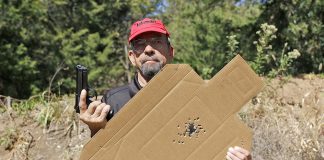 Massad Ayoob holding his Wilson Combat Beterra 92 and the target that he shot with it.