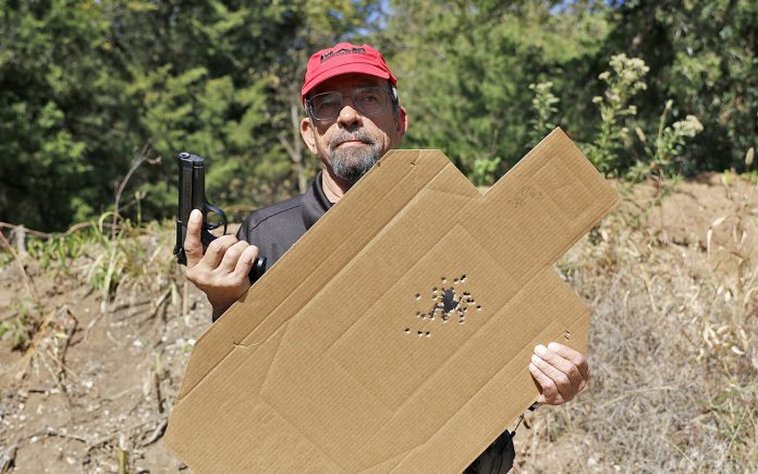 Massad Ayoob holding his Wilson Combat Beterra 92 and the target that he shot with it.
