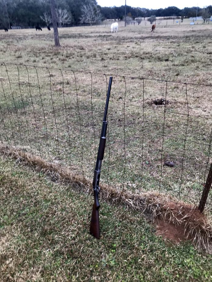 1897 Winchester shotgun leaning on a fence