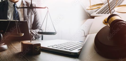 Justice and law concept. Gavel on sounding block in hand's Male judge at a courtroom, working with document law books, report the case on table in modern office.